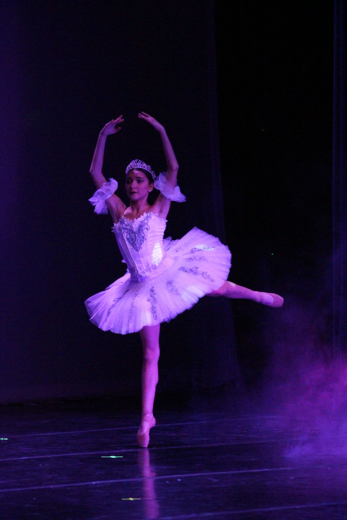 DIDC ballerina in a white tutu and tiara balancing en pointe