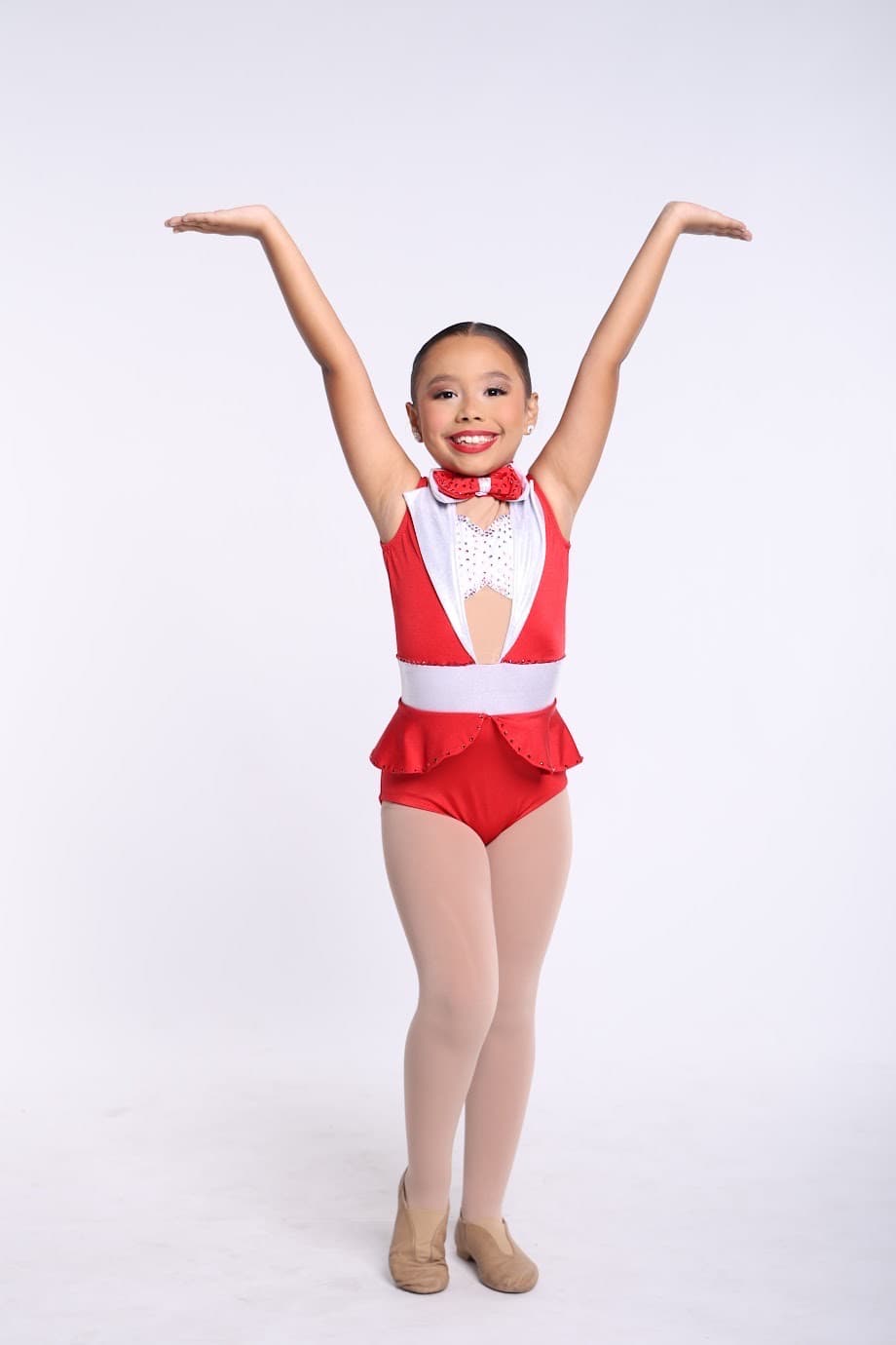 Young DIDC tap dancer in a red and white tuxedo leotard, arms up in a V